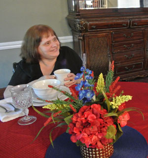 elderly woman drinking coffee at dining room table
